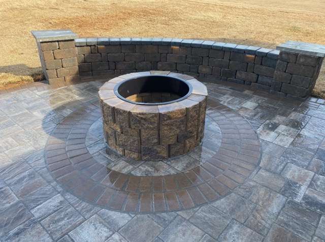 Custom stone fire pit installation surrounded by a circular stone seating area, designed for outdoor gatherings, enhancing landscape aesthetics and functionality.